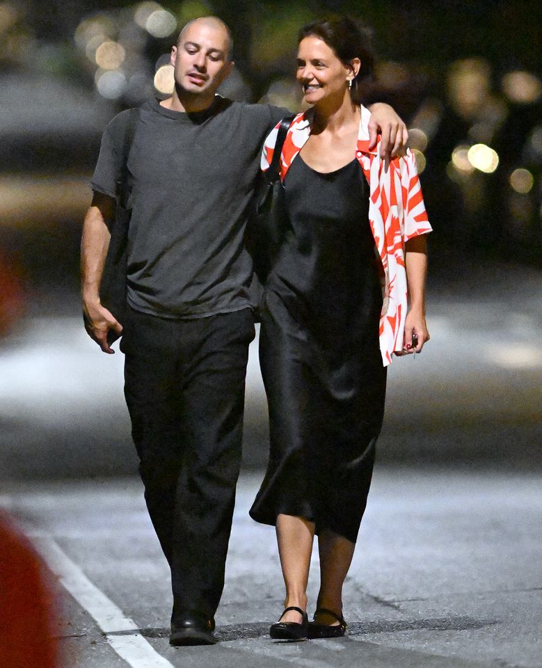 Katie Holmes walking with a person at night smiling and having a conversation