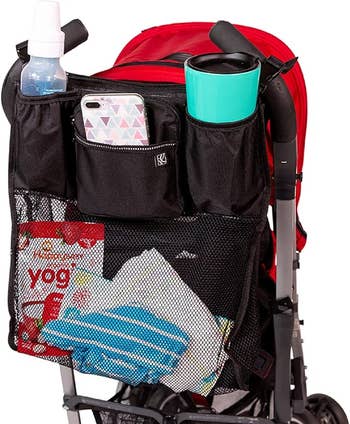Stroller with organizer attached, holding a baby bottle, phone, cup, and snacks
