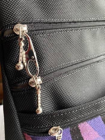 Close-up of a black textured backpack featuring zippers with unique metal zipper pulls
