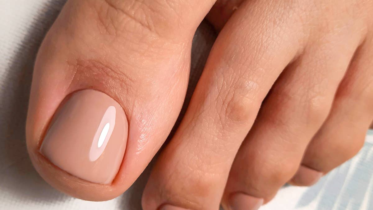 womens-pedicure-with-a-nude-gel-polish-womens-leg-with-a-delicate-coating-on-the-nails