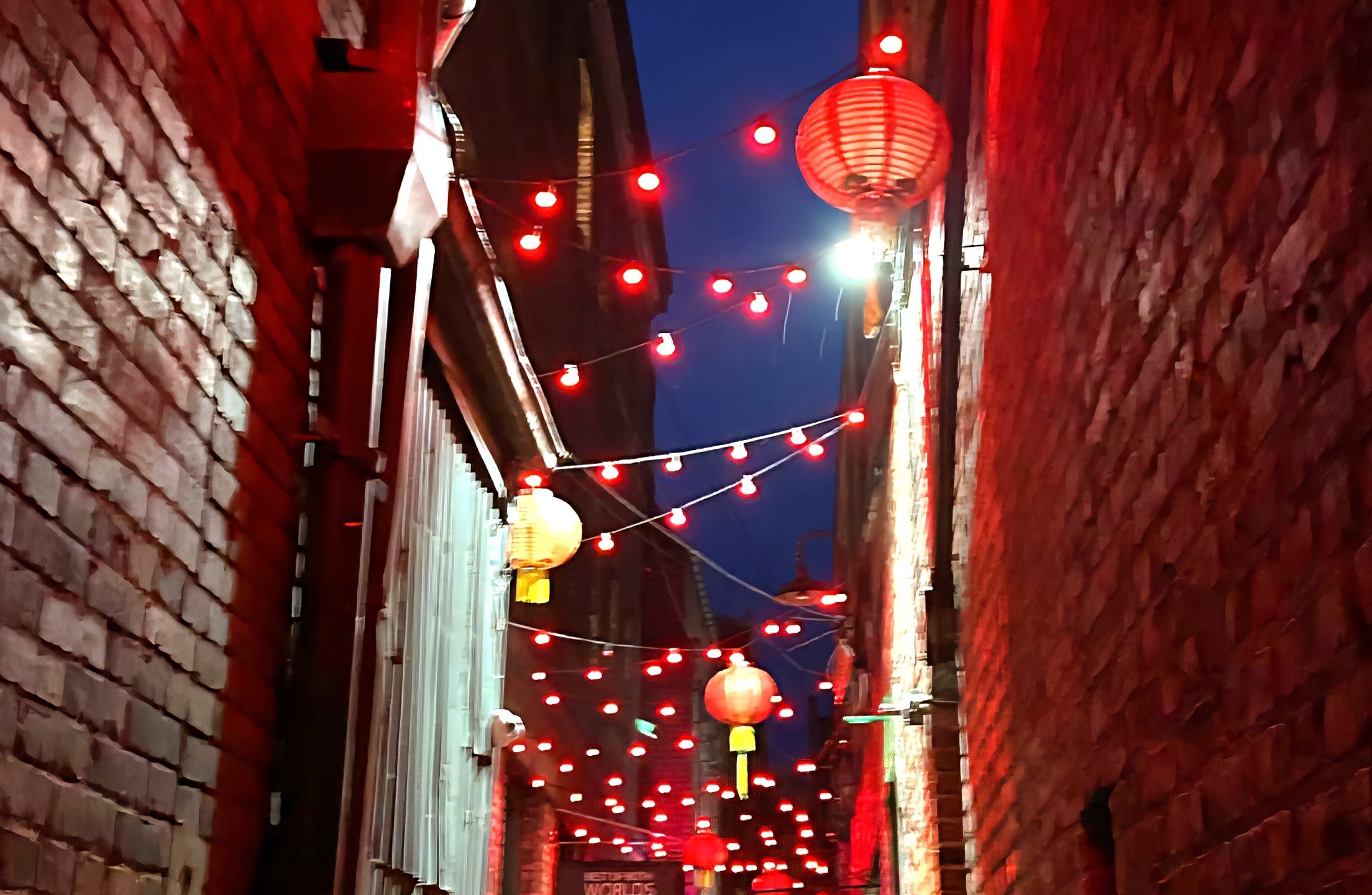 Narrow alley with string lights and lanterns, creating a romantic, intimate atmosphere