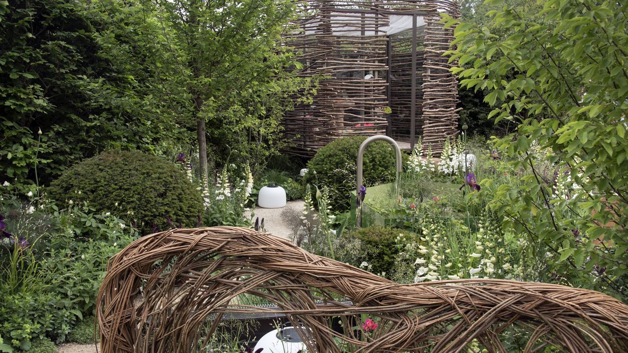 A summer garden with wicker features, trees, and white flowers at the RHS Chelsea Flower Show 2026
