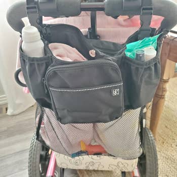 Stroller organizing bag attached to a wheelchair, filled with essentials like a water bottle, wipes, and other small items