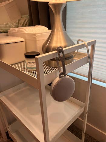 Nightstand with lamp, scented candle, and a portable Bluetooth speaker hanging. Ideal setup for creating a relaxing atmosphere