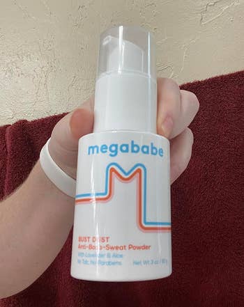 Person holding a bottle of Megababe Bust Dust Anti-Boob-Sweat Powder, labeled with