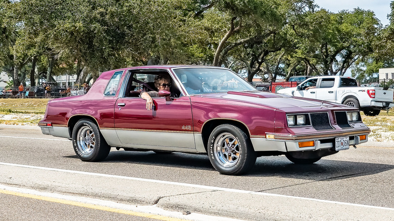 Red Olds Cutlass 442 leaving a parking lot