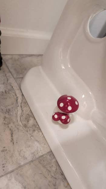 Ceramic mushroom decor placed on a bathroom floor near a white toilet base