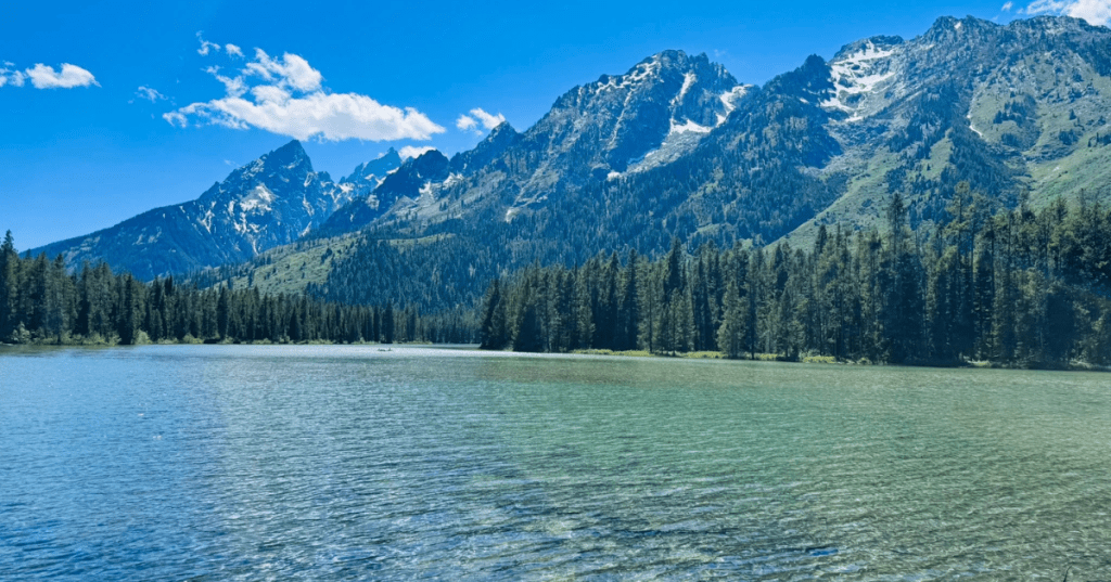 Clear Leigh Lake sits at the base of the Teton Mountains on an early summer day in Grand Teton National Park.