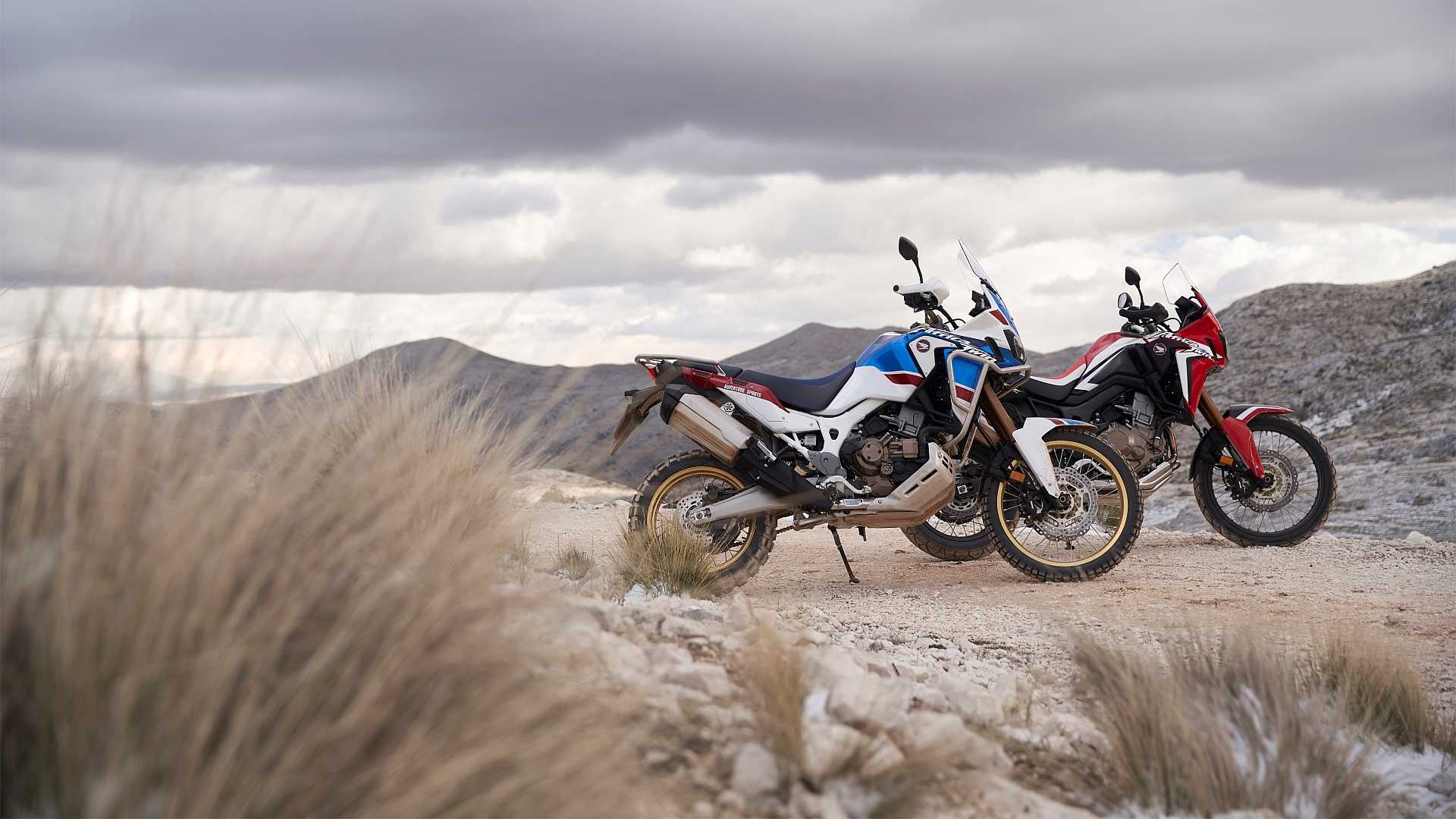 Still shot of two 2016 Honda CRF1000L Africa Twins parked in a desert locale with mountains in the background