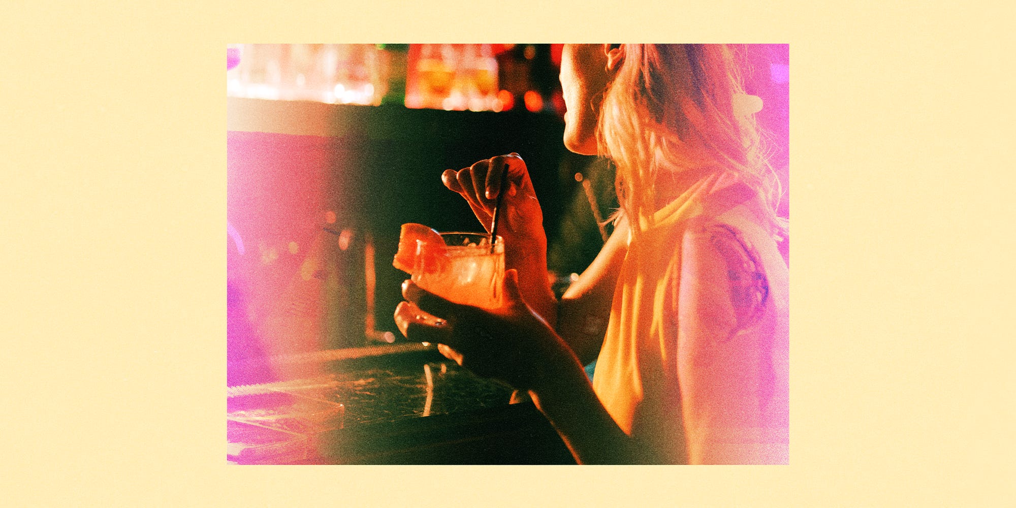 Young woman enjoying a cocktail at a bar.