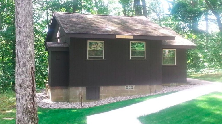 A large wooden cabin on the grass among the trees in Trine State Recreation Area