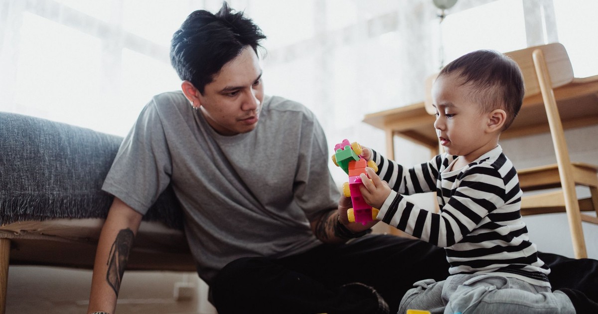 A father and son enjoy quality time indoors, building with colorful blocks together.