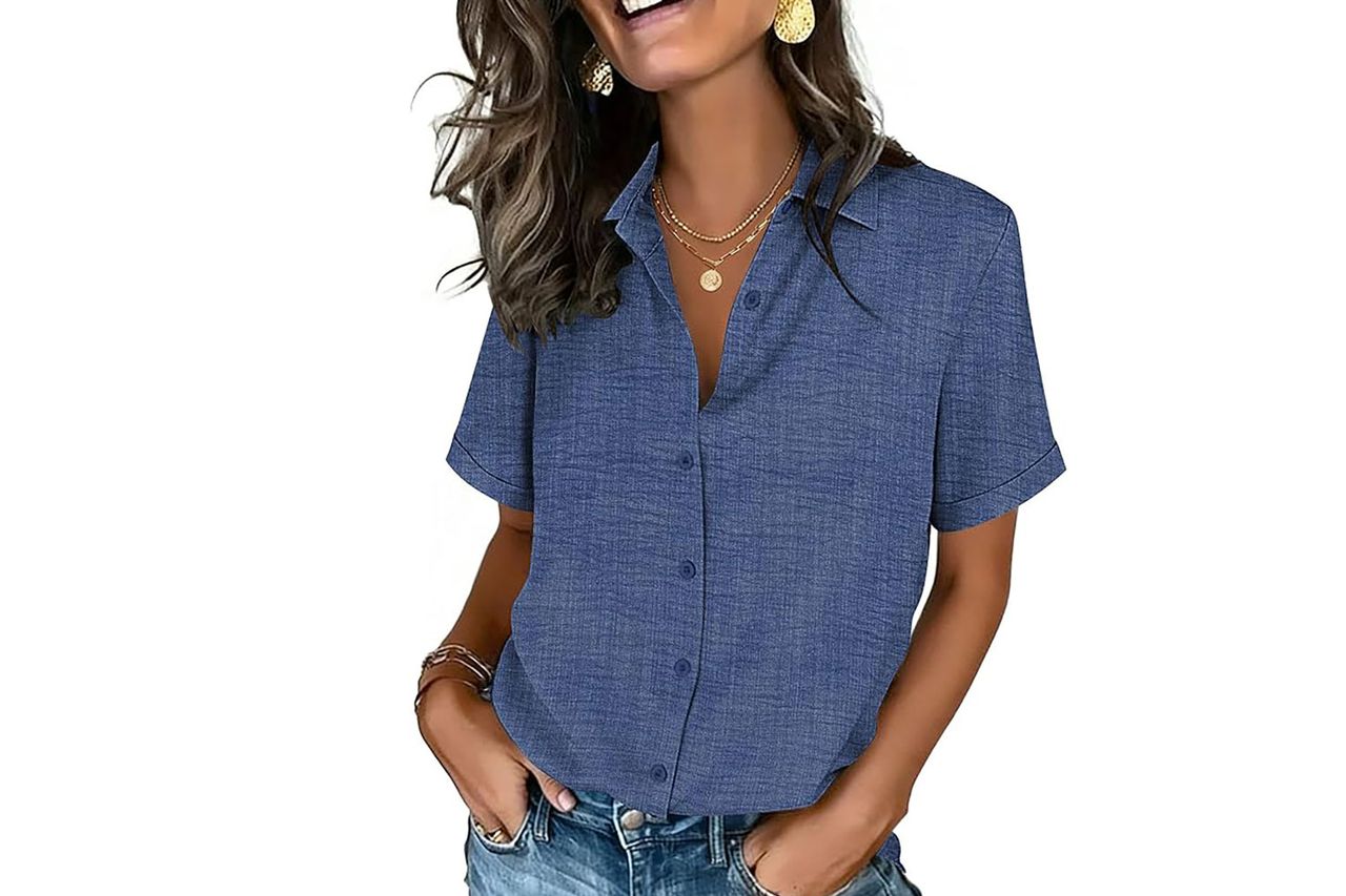 A woman wearing a shortsleeve buttondown shirt and jeans smiling with her hands in her pockets