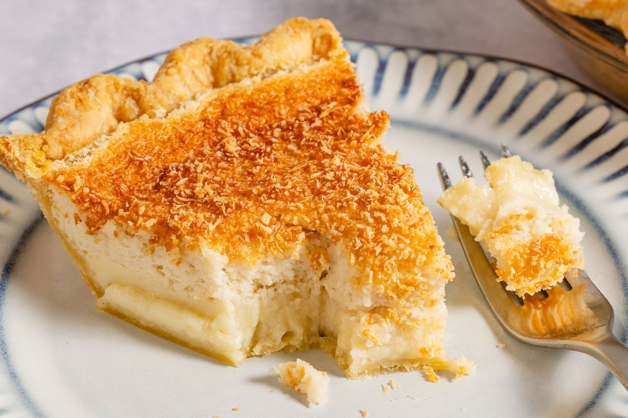 A slice of coconut cream pie on a plate with a fork beside it