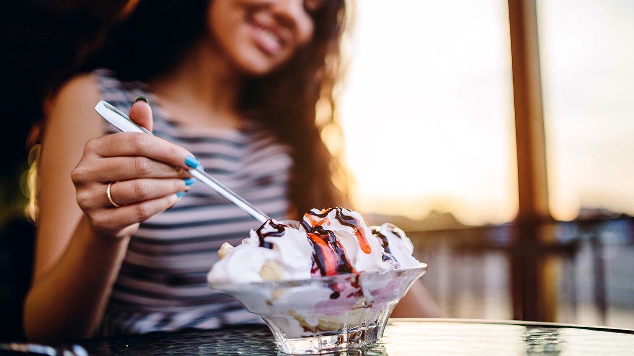 A woman eats a banana split.