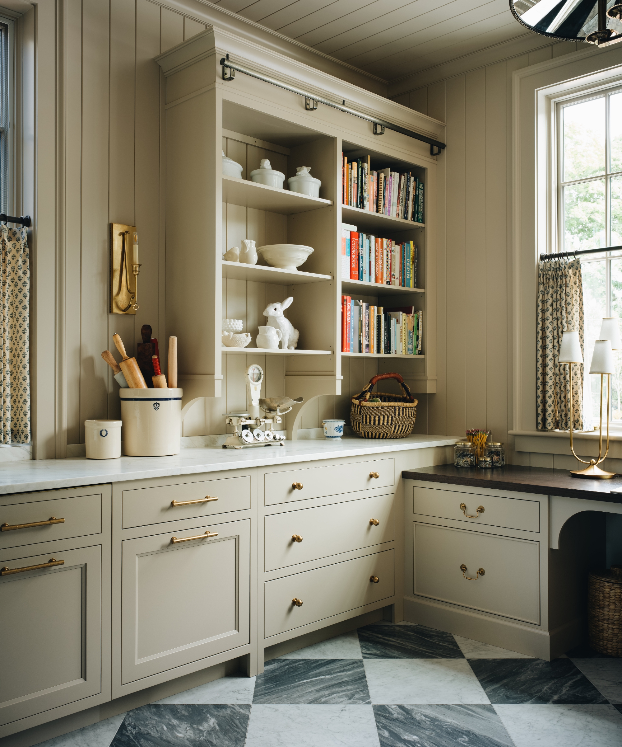 The corner of a baker's kitchen with beige cabinetry, marble countertops, and checkerboard flooring