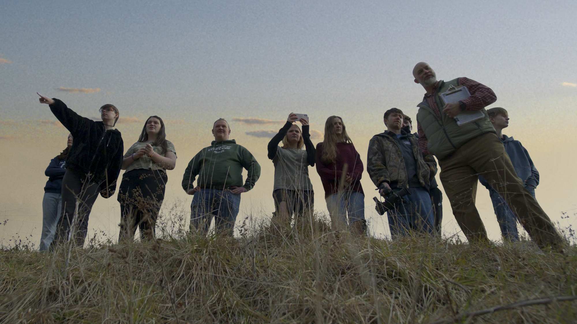 Alex Campbell and his sociology students stand in a field on Murder 101.