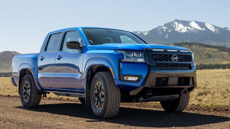 Front 3/4 view of blue Nissan Frontier parked on trail.