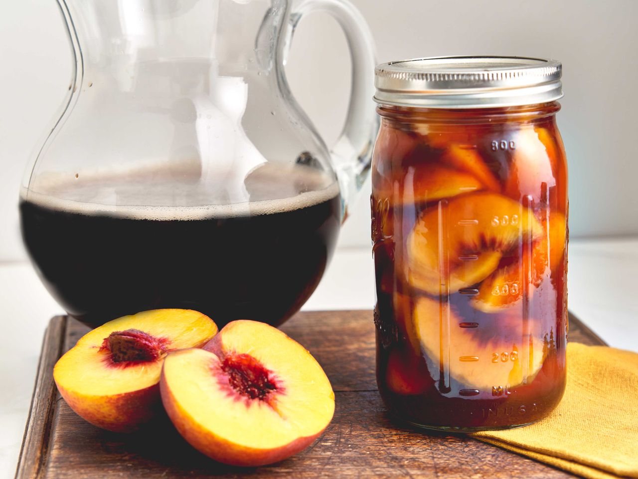 Sweet tea peaches in jar and 2 halves on cutting board