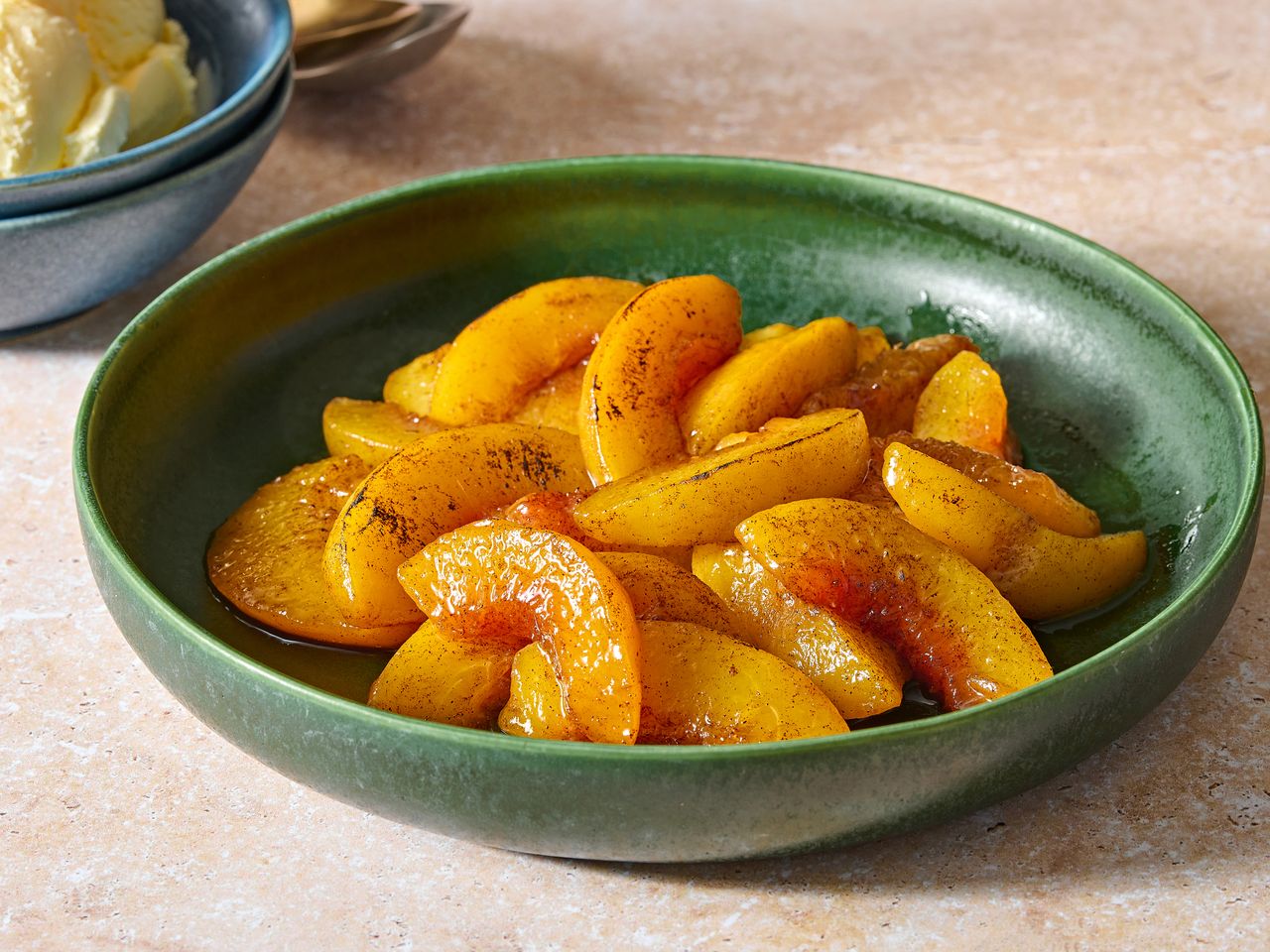 A green bowl with sliced grilled peaches