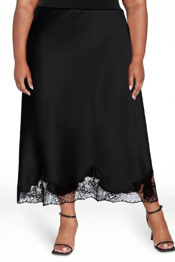 Model wearing a sleek, ankle-length satin skirt with lace trim and strappy high-heels, featured in a shopping article