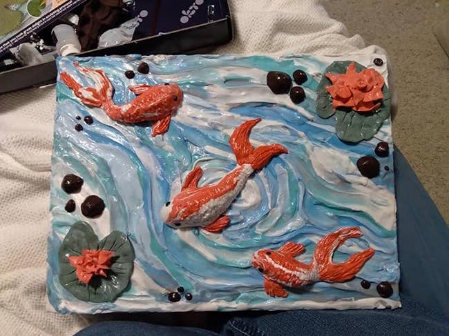 Textured art piece with koi fish swimming in a swirling water design, surrounded by lily pads and flowers