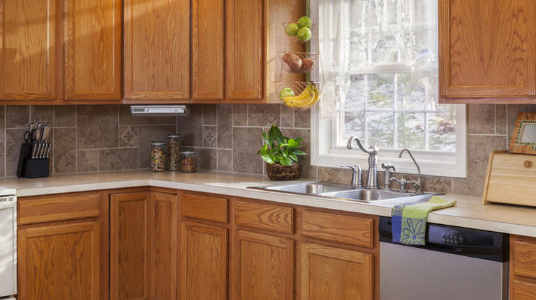 She gives orange oak cabinets a moody transformation with a clever DIY