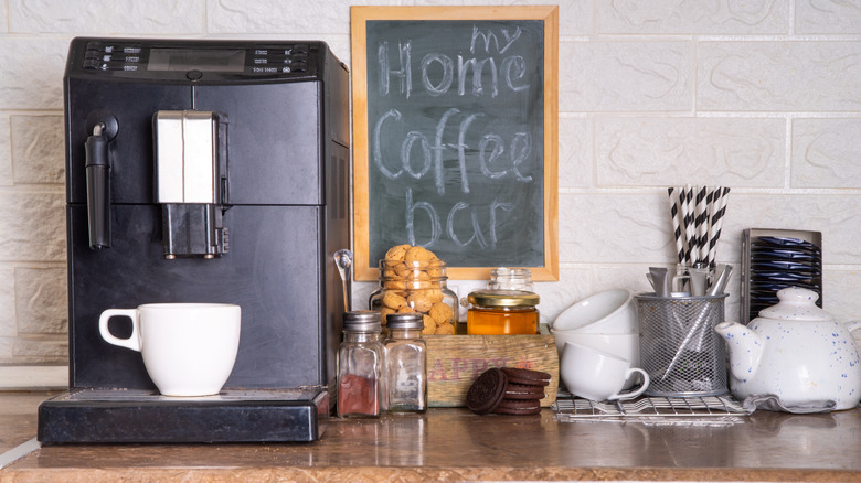 A coffee station with spices, teapots, coffee cuts, honey, and stir sticks