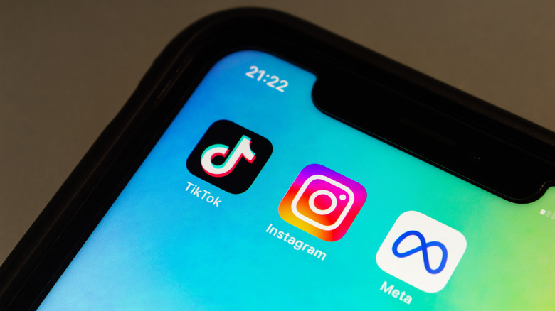 TikTok, Instagram, and Meta apps on an iPhone placed against a brown background