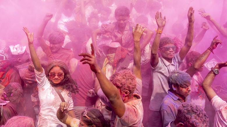 People dancing in colored powder during Holi