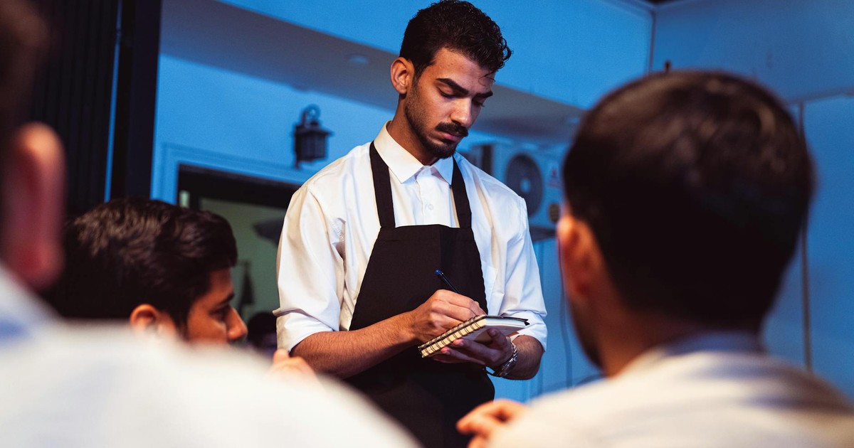 Attentive waiter writing down a customer's order in a cozy indoor restaurant.