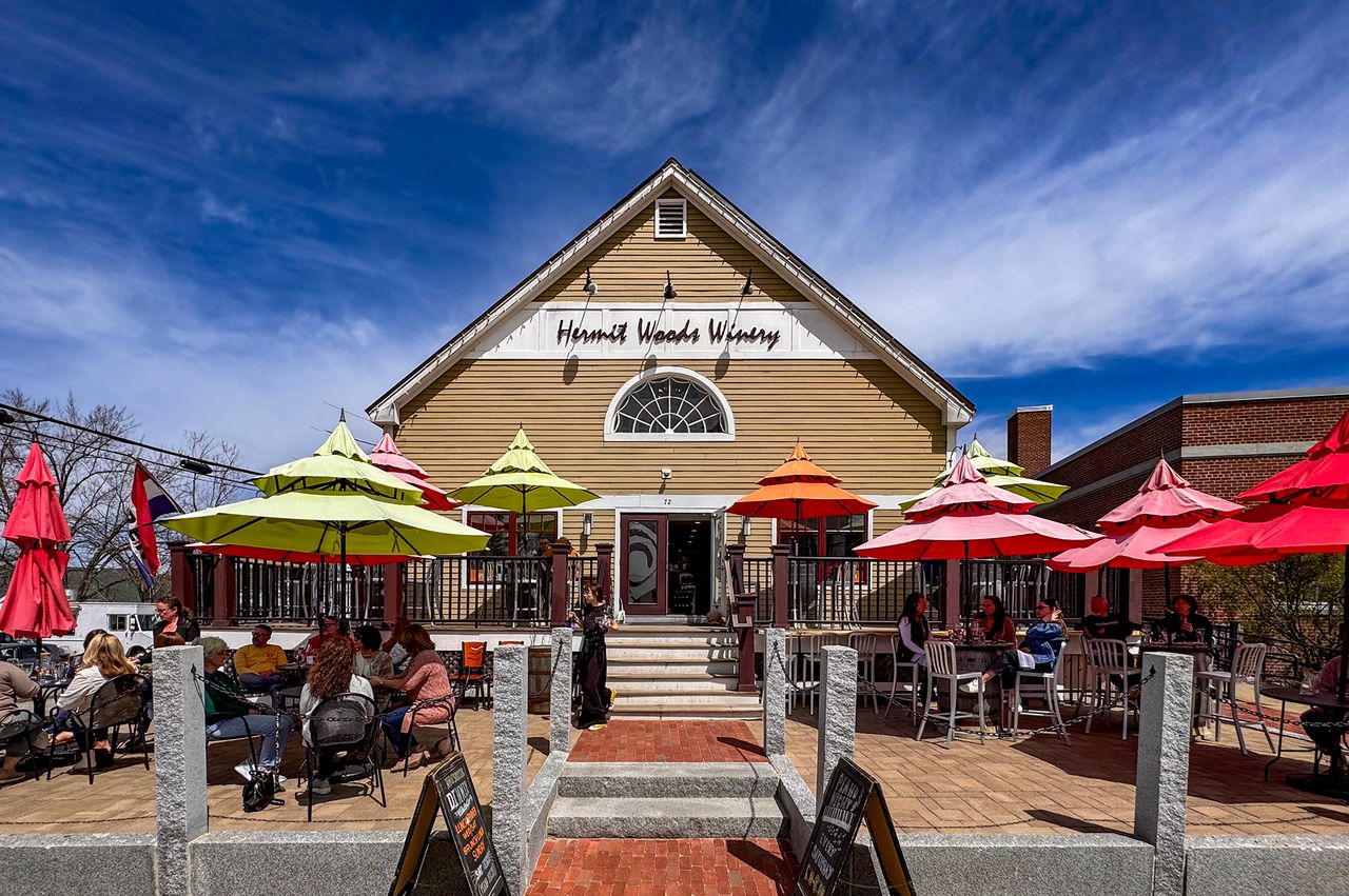 Hermit Woods Winery with outdoor seating and colorful umbrellas people gathered and enjoying the outdoor area