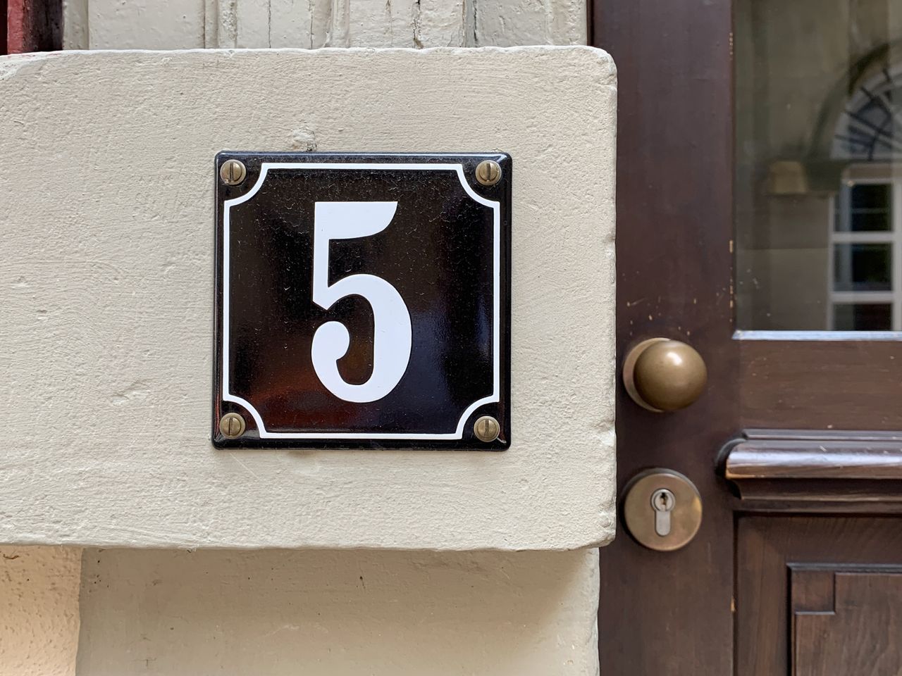 House number 5 on the outside of a residence with a wooden door and brass knob