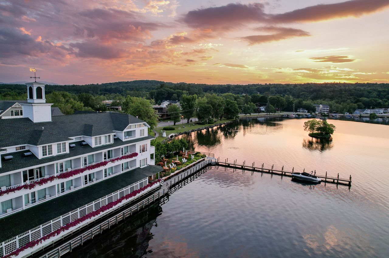 A lakeside resort building with a pier and scenic view at sunset located at Mill Falls in Meredith New Hampshire