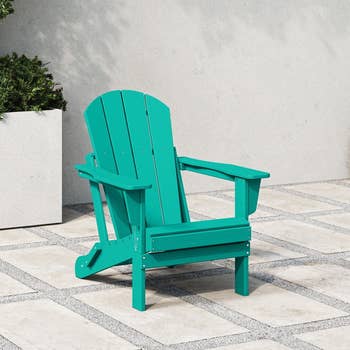 Teal Adirondack chair on a patio with potted plants in the background