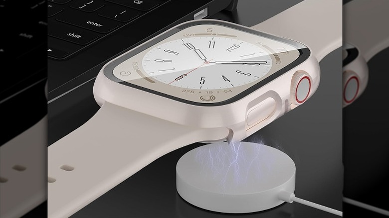 White Apple Watch encased in a white case placed on top of a charger.