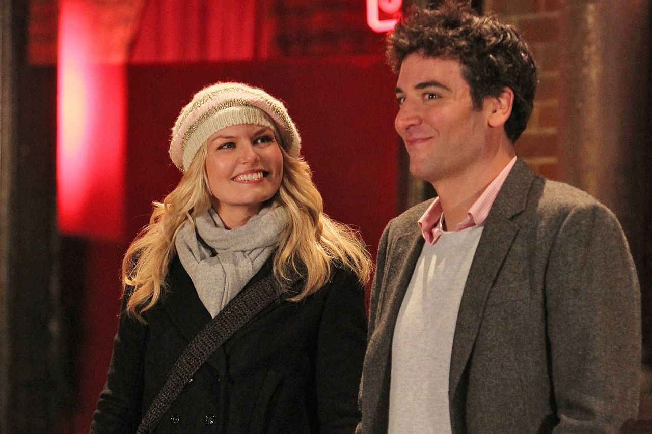 Jennifer Morrison and Josh Radnor standing together indoors engaged in conversation