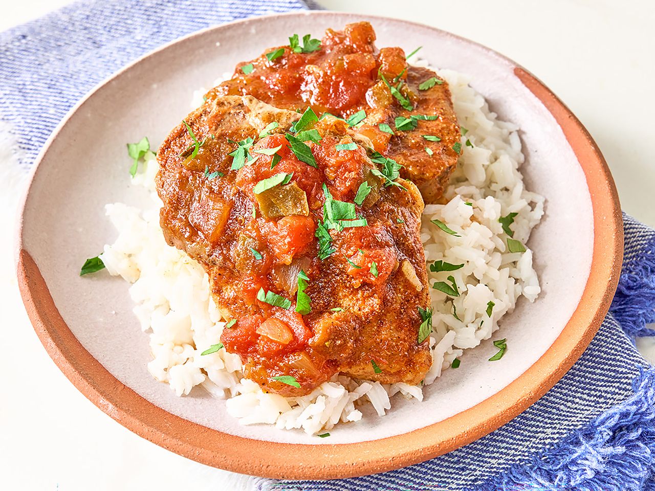 peach pork picante over rice on plate with blue napkin