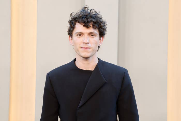 Person in a structured black blazer with curly hair, attending an event