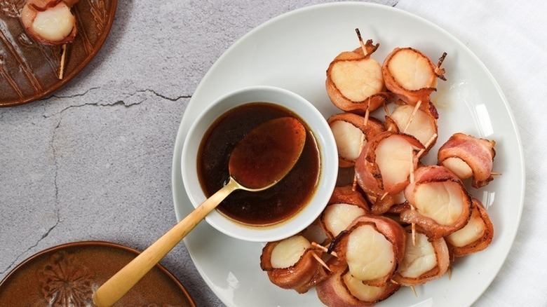 Bacon-wrapped scallops on plate with small bowl of apple cider sauce