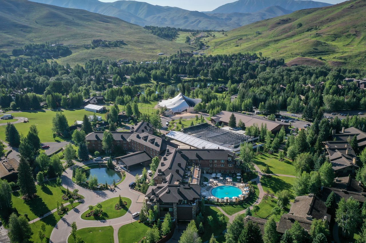 Aerial view of a resort with a pool surrounded by trees and mountains