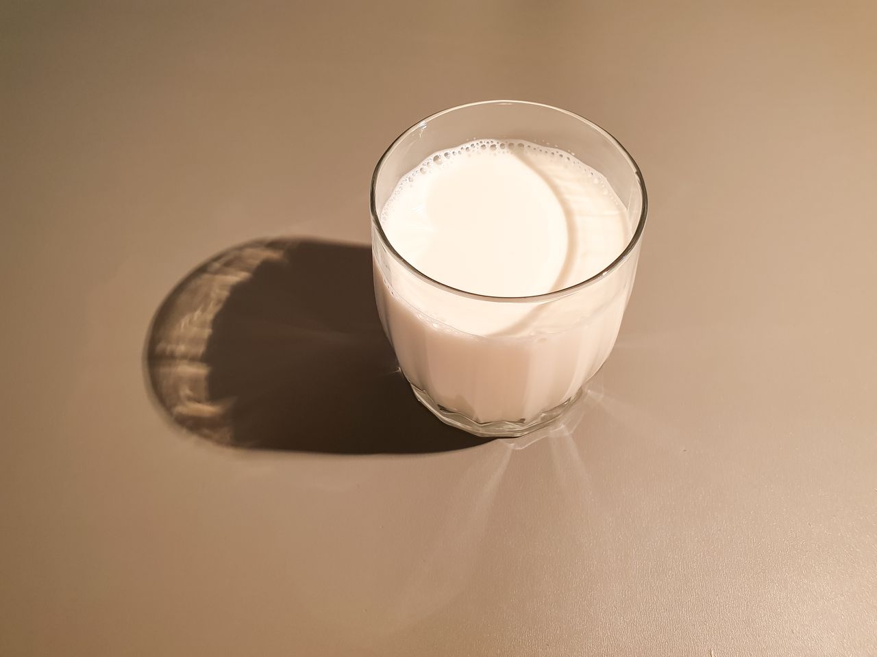 A glass of milk on a plain surface