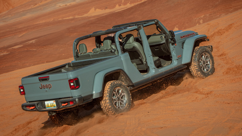 Rear 3/4 view of gray Jeep Gladiator climbing sandy hill.