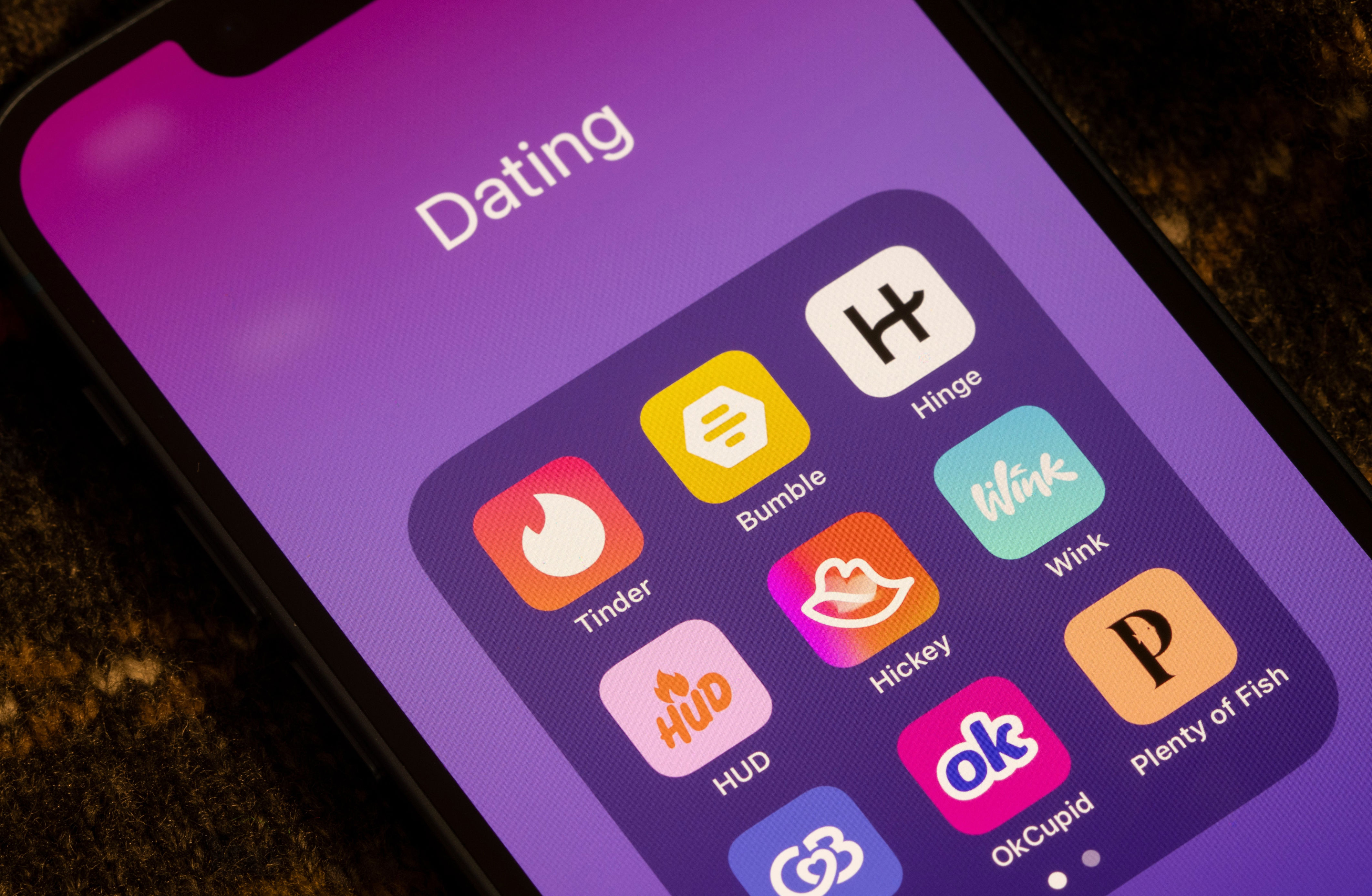 Smartphone displaying a folder with dating app icons including Tinder, Bumble, and Hinge