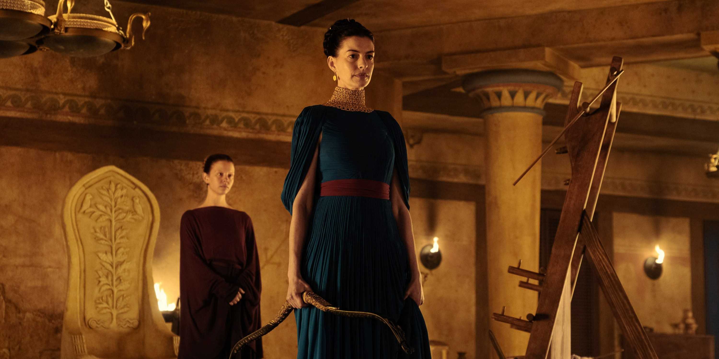 Penelope (Anne Hathway) holding Odysseus's bowPenelope (Anne Hathaway) holding Odysseus's bow and Melantho (Mia Goth) standing behind her in The Odyssey. and Melantho (Mia Goth) behind her in The Odyssey.