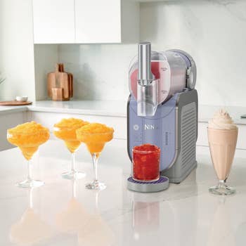 Kitchen appliance on counter with drinks: two slushy margaritas, pomegranate shave ice, and frozen coffee