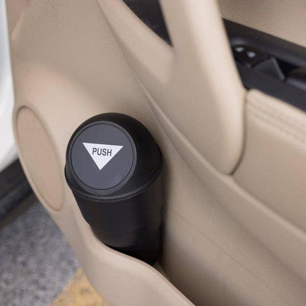 Car door compartment with a black cylindrical trash bin labeled
