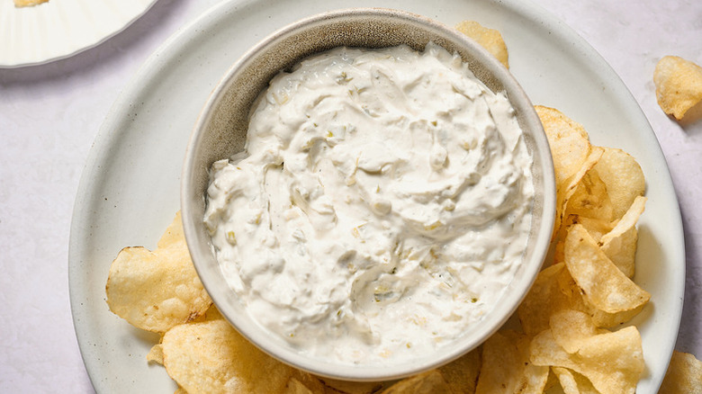 Creamy green onion dip in bowl, served with potato chips