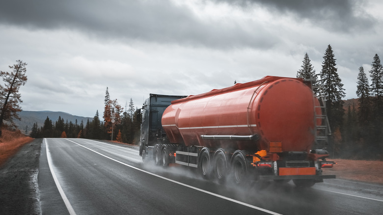 Tanker truck driving on hilly road in wet conditions