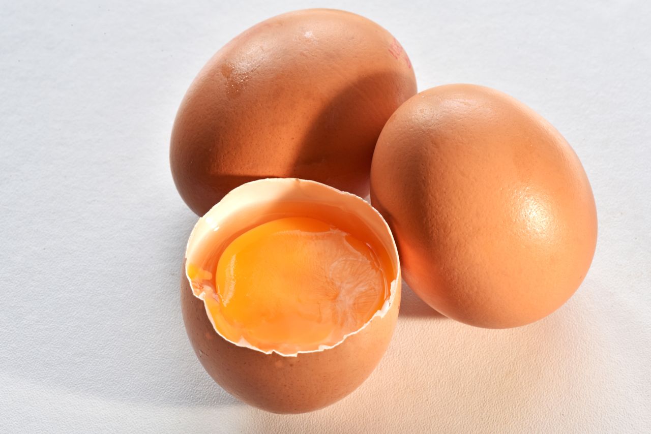 Three eggs one cracked to reveal the yolk
